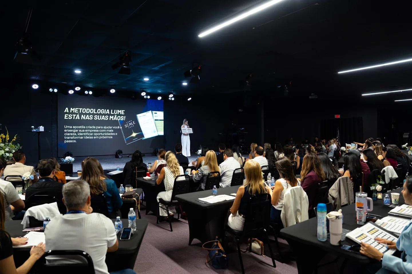 Plateia acompanhando a apresentação da metodologia no palco